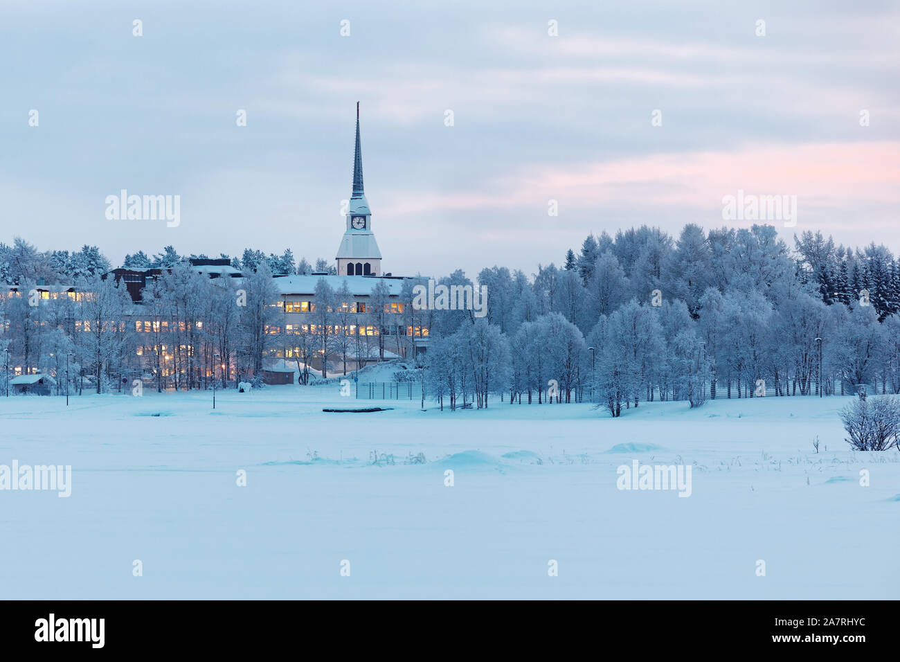 Paesaggio invernale con lago ghiacciato e la guglia della chiesa nel pomeriggio di Kuusamo, Finlandia Foto Stock
