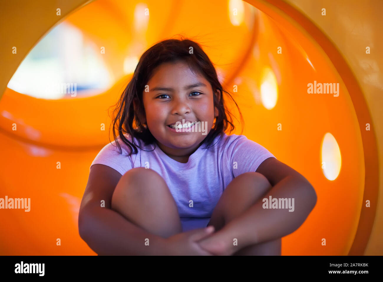 9 A 9 anno vecchia ragazza divertirsi giocando in un parco giochi di colore giallo diapositiva. Foto Stock