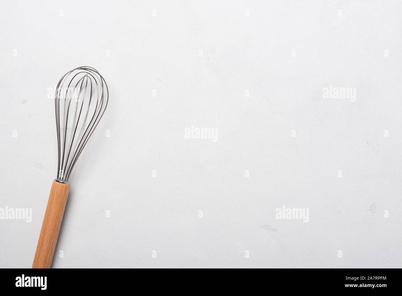 Mescolare con una frusta per la cottura di uova miscelatore del battitore cercatore con manico in legno sulla tavola di stucco vista superiore Foto Stock