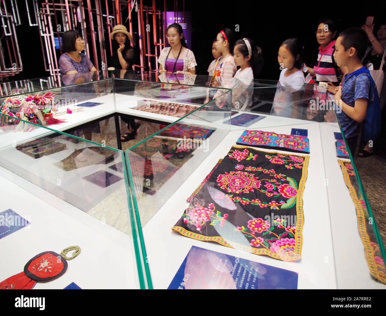 Visitatori visualizzare un oggetto d'arte etnica con motivi decorativi in occasione di una mostra presso il Beijing World Art Museum di Pechino, Cina, 7 agosto 2019. Foto Stock