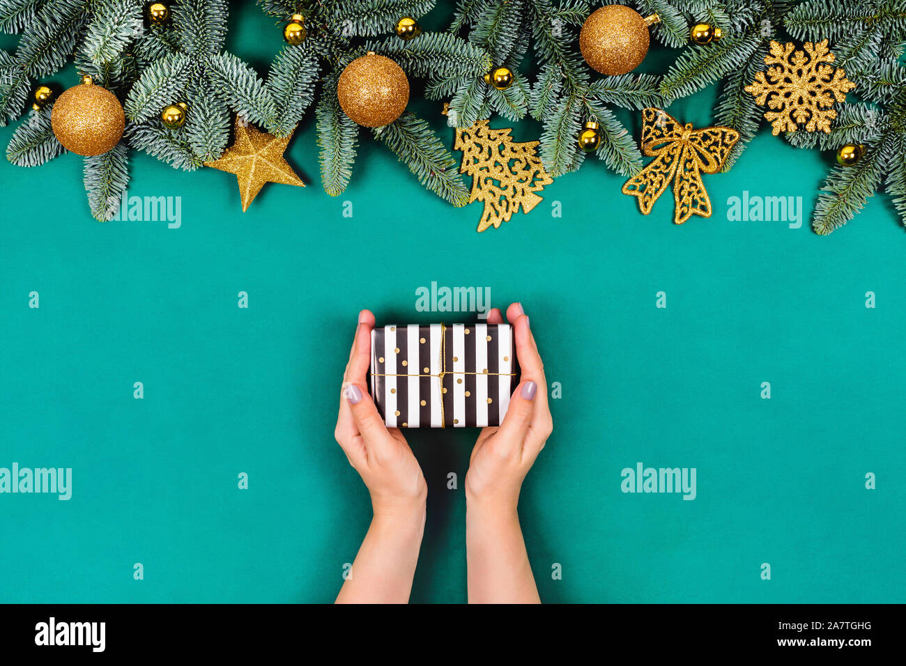 Nuovo anno e concetto di Natale. Telaio dell albero di Natale rami decorato con sfere di oro e giocattoli. Presente casella in mani. Appartamento laico, vista dall'alto, copia sp Foto Stock