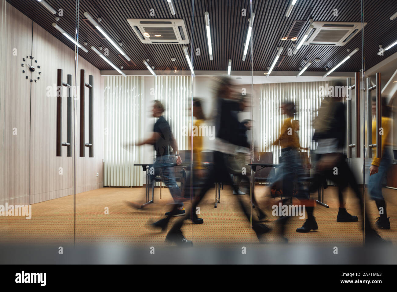 Un gruppo di dipendenti in sede al centro di coworking. La gente di affari a piedi a moderno spazio aperto. Motion Blur. Concetto Foto Stock