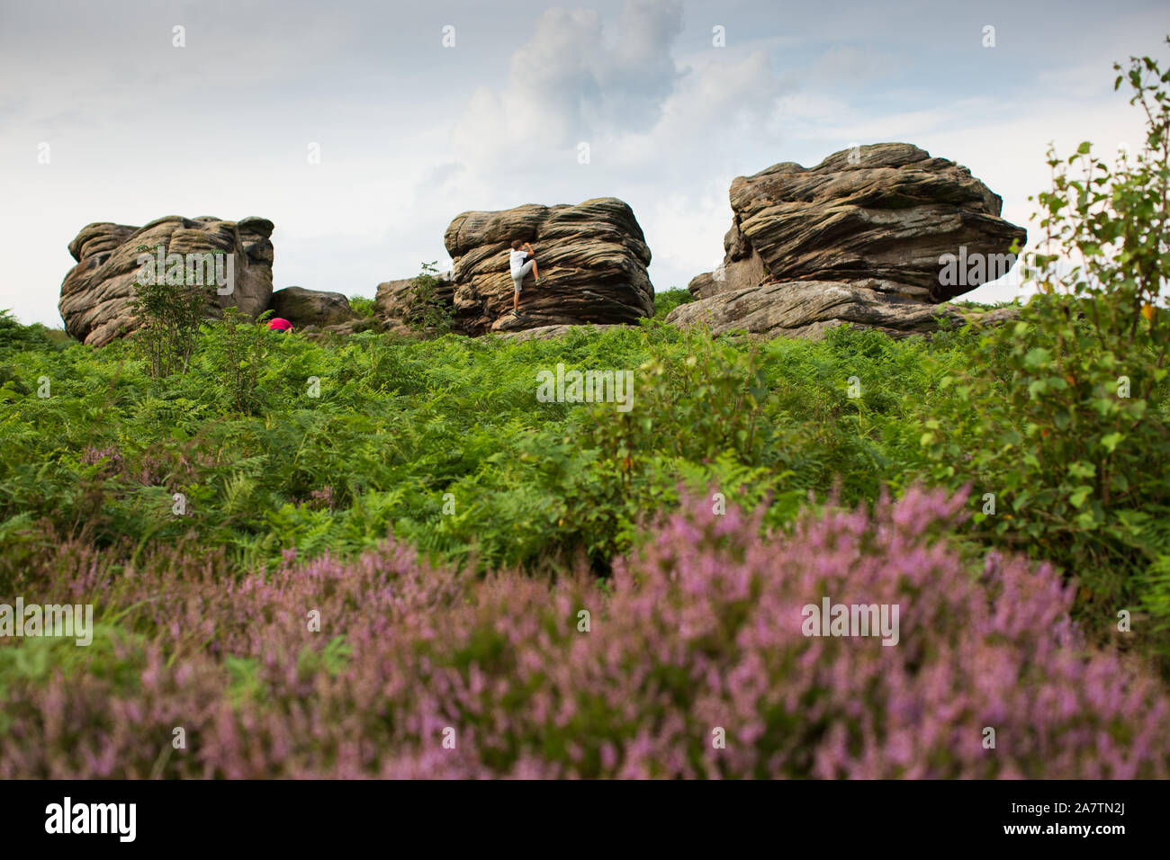 Ragazzo giovane arrampicata su tre navi, Birchen Edge, Peak District. Foto Stock