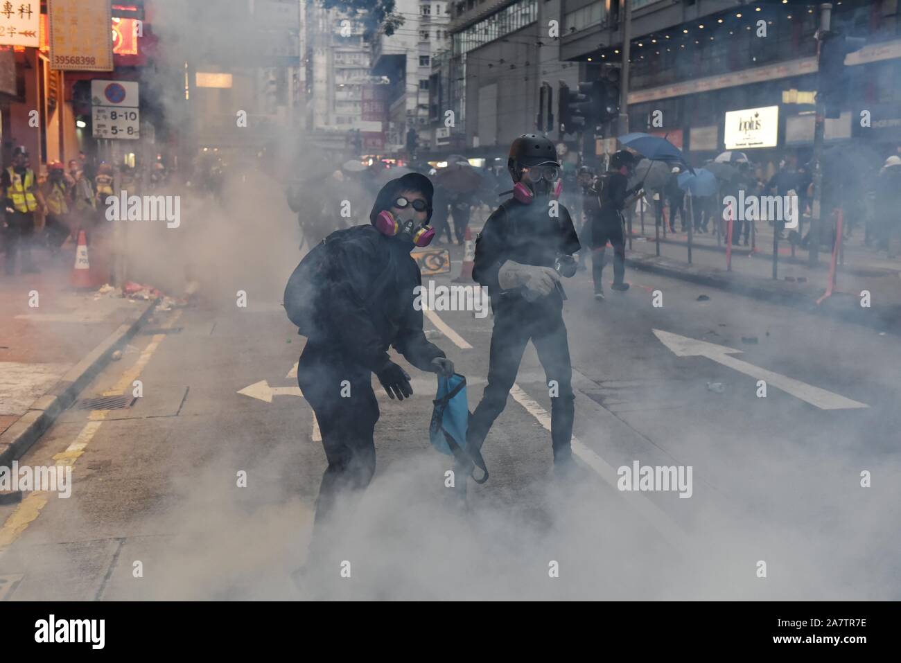 Manifestanti indossare le maschere nel mezzo di gas lacrimogeno fumo durante la dimostrazione.Il movimento in favore della democrazia è stata originata con il coro di proteste contro la legge in materia di estradizione. Hong Kong è entrato ventiduesima settimana ha continuato a proteste di massa. Foto Stock