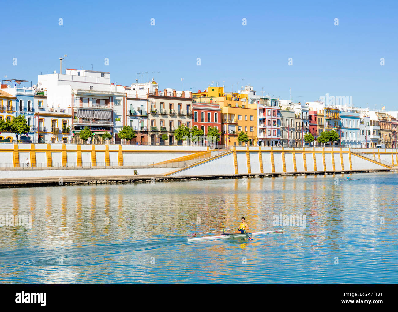 Case colorate lungo il Triana rive del fiume Guadalquivir con un vogatore Sevilla Siviglia Spagna Siviglia Andalusia Spagna UE Europa Foto Stock