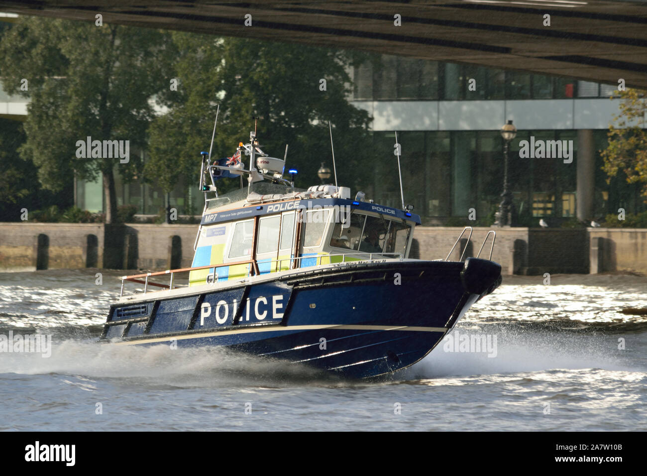 Incontrato barca di polizia su una luce blu correre lungo il Tamigi passando sotto il ponte di Londra Foto Stock