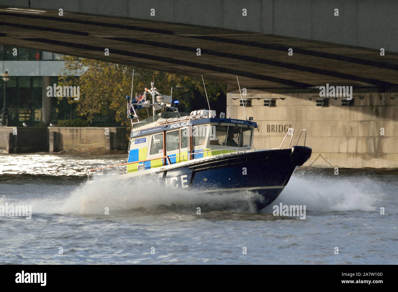 Incontrato barca di polizia su una luce blu correre lungo il Tamigi passando sotto il ponte di Londra Foto Stock