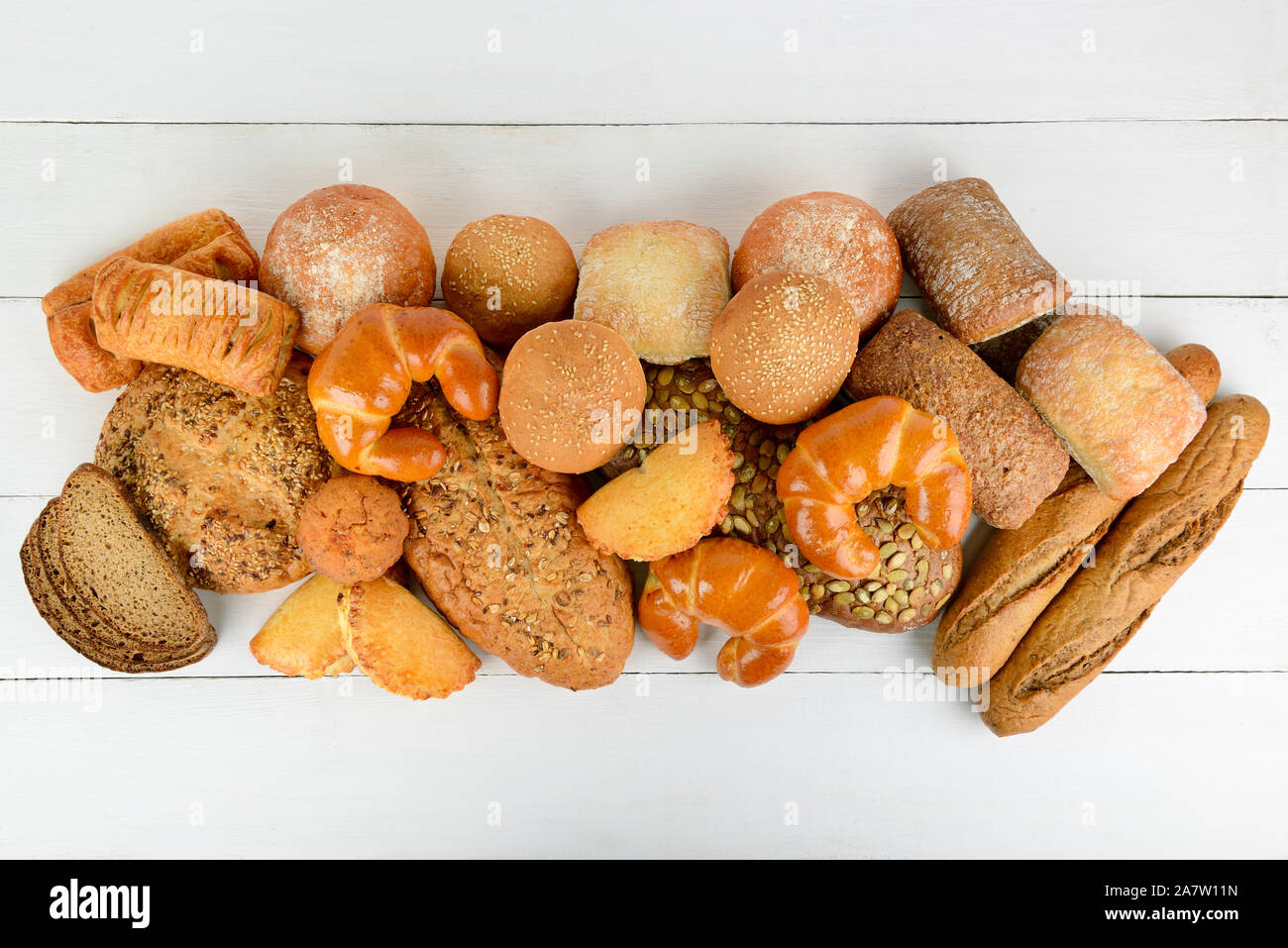 Pane, panini, croissant e altri prodotti da forno su un tavolo di legno. Vista dall'alto. Spazio di copia Foto Stock