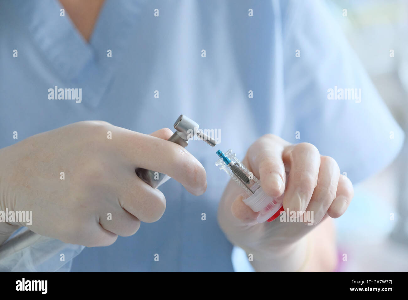 Le mani di un chirurgo dentista in guanti di protezione con uno strumento chirurgico Foto Stock Le mani di un chirurgo dentista in guanti di protezione con uno strumento chirurgico Foto Stock