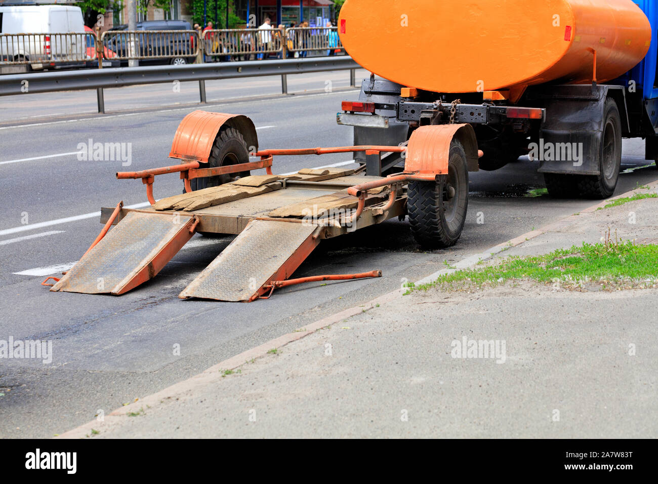 Un vecchio basso-platform il rimorchio è agganciato ad un vecchio camion che sorge su di una carreggiata stradale. Foto Stock Un vecchio basso-platform il rimorchio è agganciato ad un vecchio camion che sorge su di una carreggiata stradale. Foto Stock