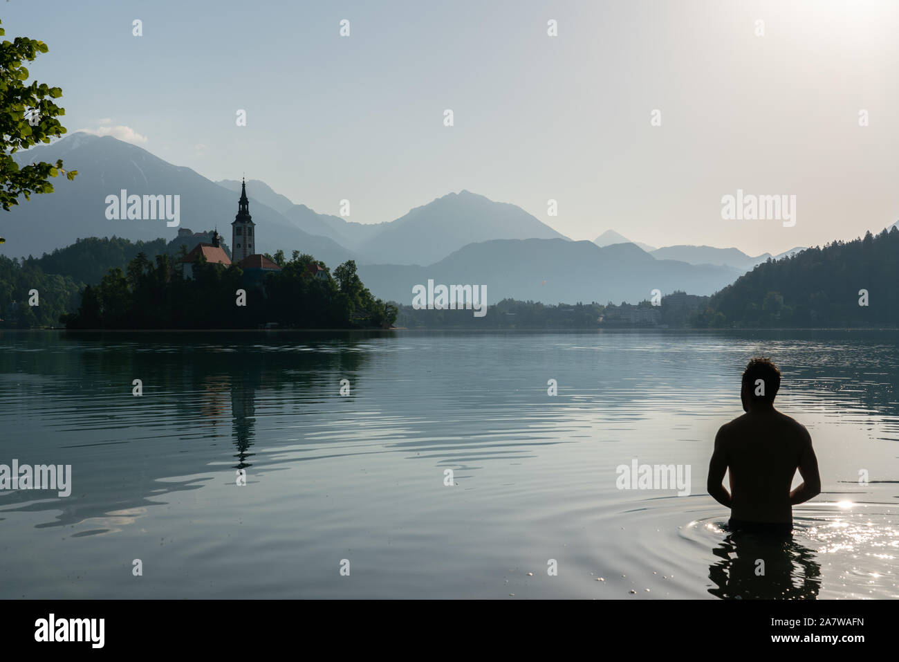 Silhouette di un uomo europeo la balneazione sul Lago di Bled mentre si pratica il Wim Hof ​​meditation metodo Foto Stock