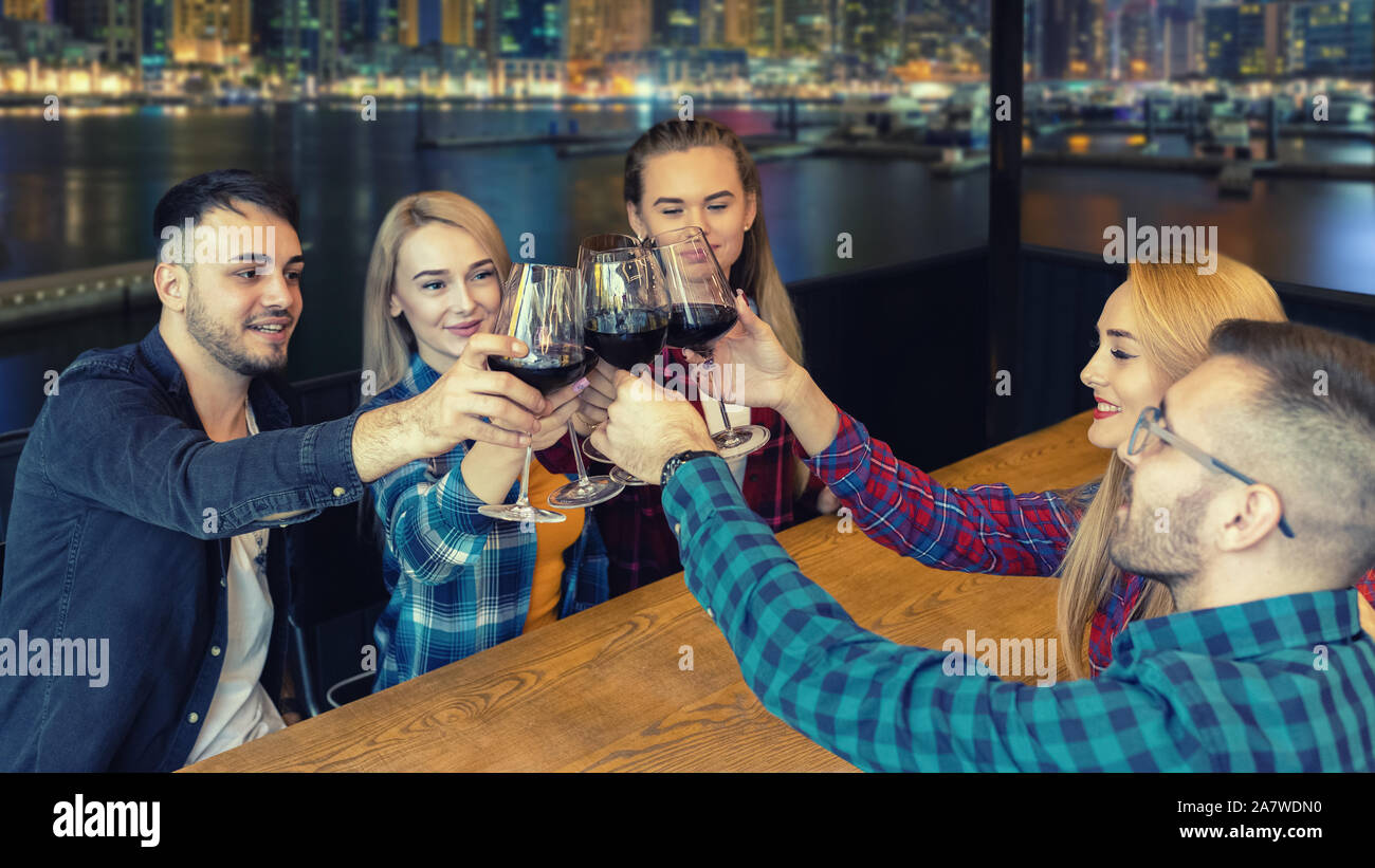 Gruppo di amici migliori di bere il vino alla sera fashion bar panoramico ristorante. Foto Stock