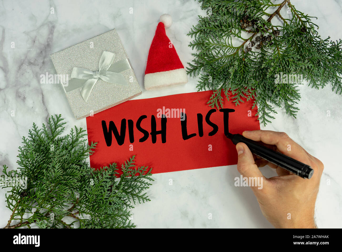La lista dei desideri su marmo Natale sfondo con uomo a scrivere la sua lista dei desideri telaio pino , Foto Stock
