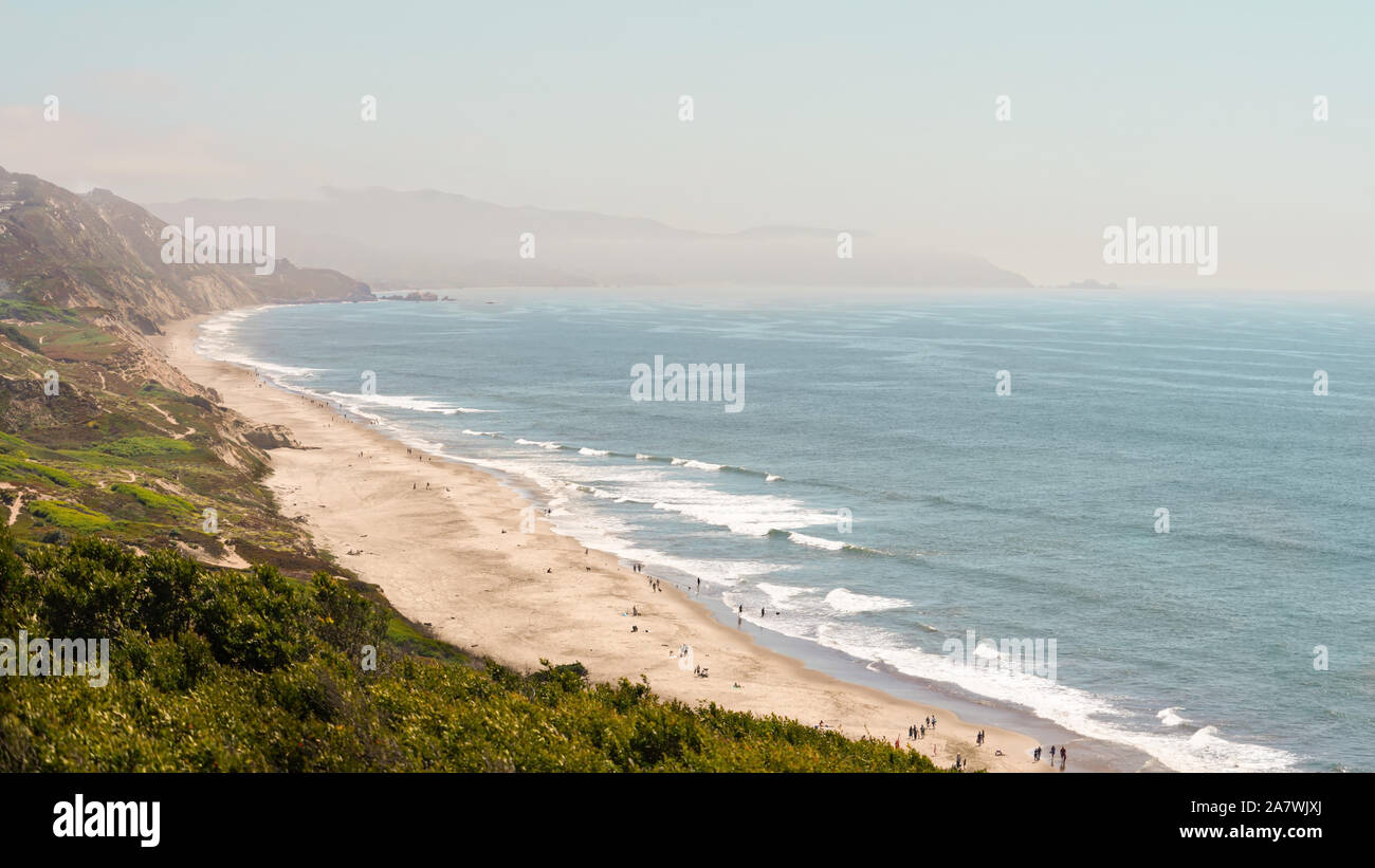 Vista dell'Oceano Pacifico dall'alto su impianto coperto duna di sabbia cliff, foggy sky, laminazione marea sulla spiaggia sabbiosa Foto Stock