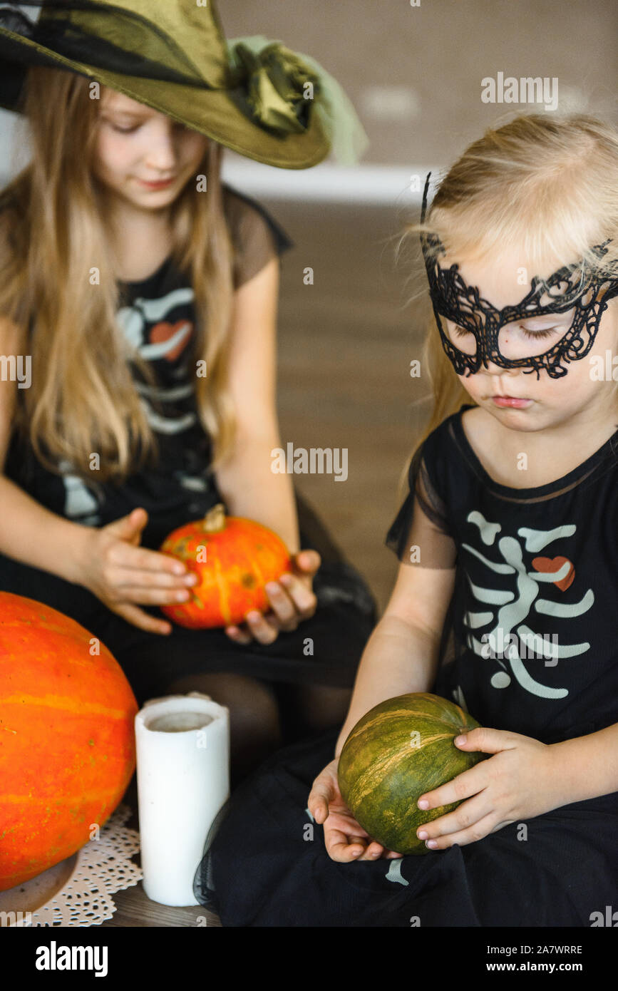 Due sorelle vestito per la festa di Halloween in costumi di scheletro con zucche Foto Stock