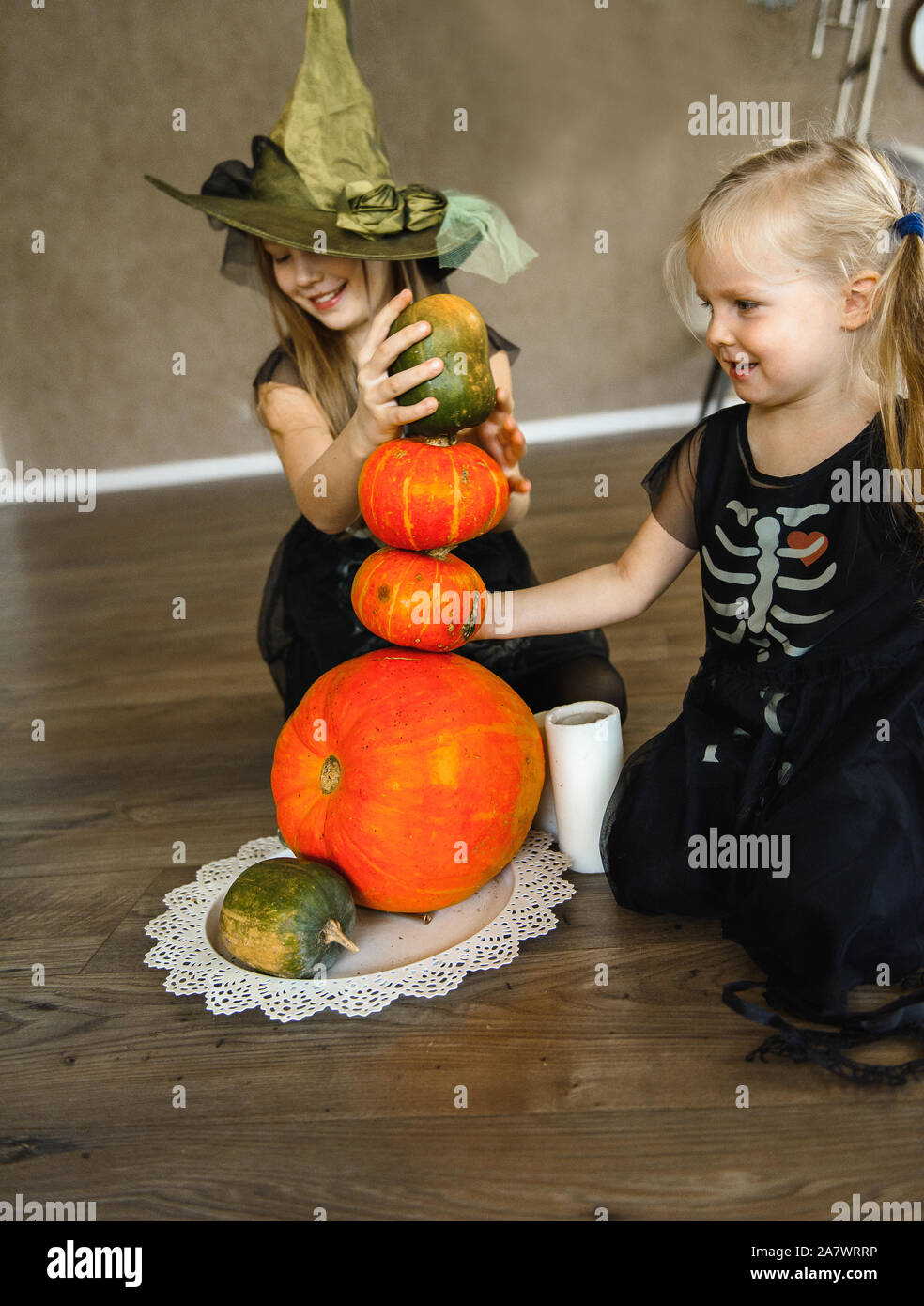 Due sorelle vestito per la festa di Halloween in costumi di scheletro con zucche Foto Stock