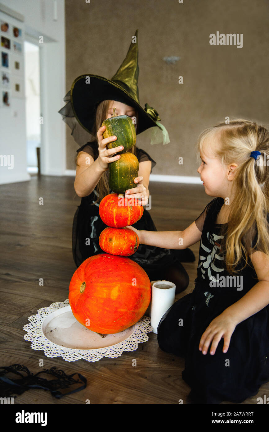 Due sorelle vestito per la festa di Halloween in costumi di scheletro con zucche Foto Stock