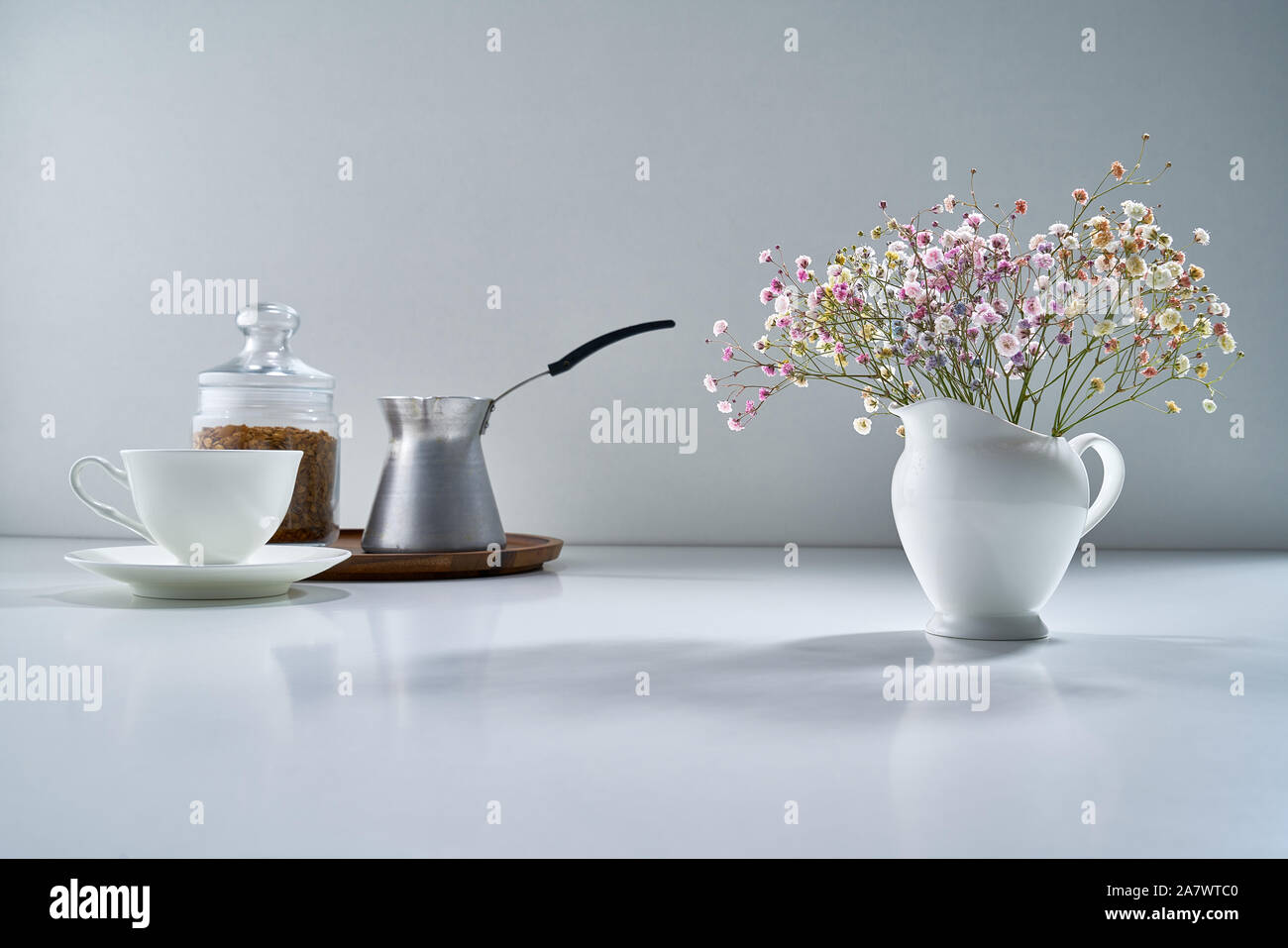Composizione con porcellana bianca tè-ware su uno sfondo grigio chiaro con un delicato bouquet di fiori Foto Stock