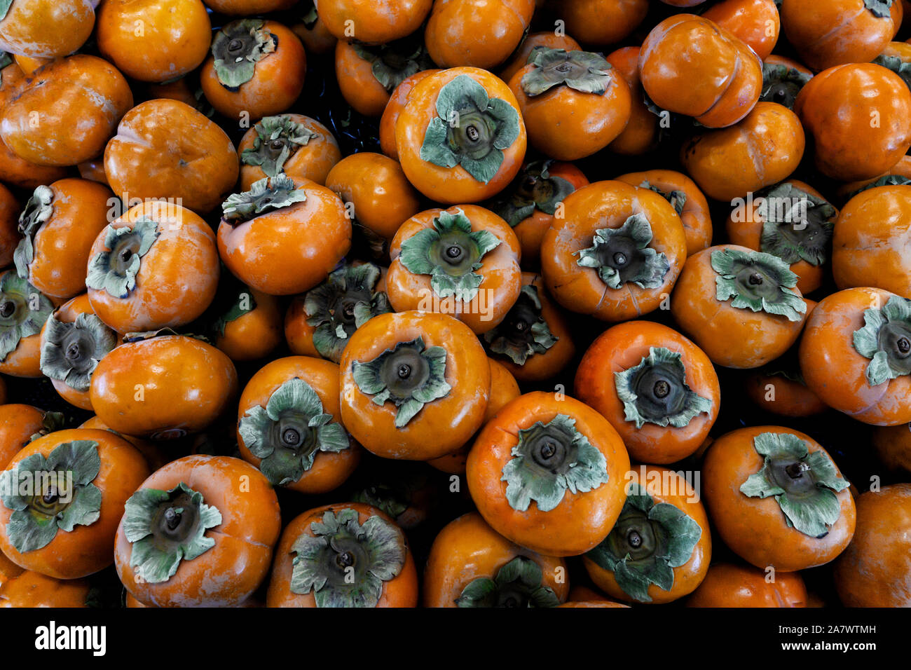 Fresche e mature kaki. Persimmon organica frutta nella pila presso gli agricoltori locali del mercato. Cachi sfondo. Foto Stock