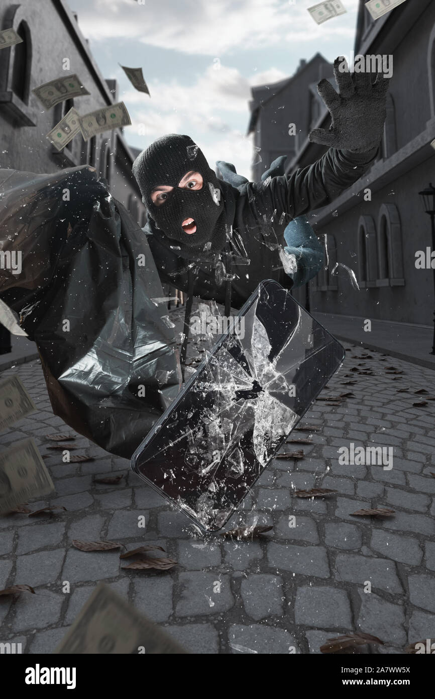 Sorpresi ladro con passamontagna e moneybag slittamenti e battenti dopo aver infranto smart phone che cadendo per strada Foto Stock