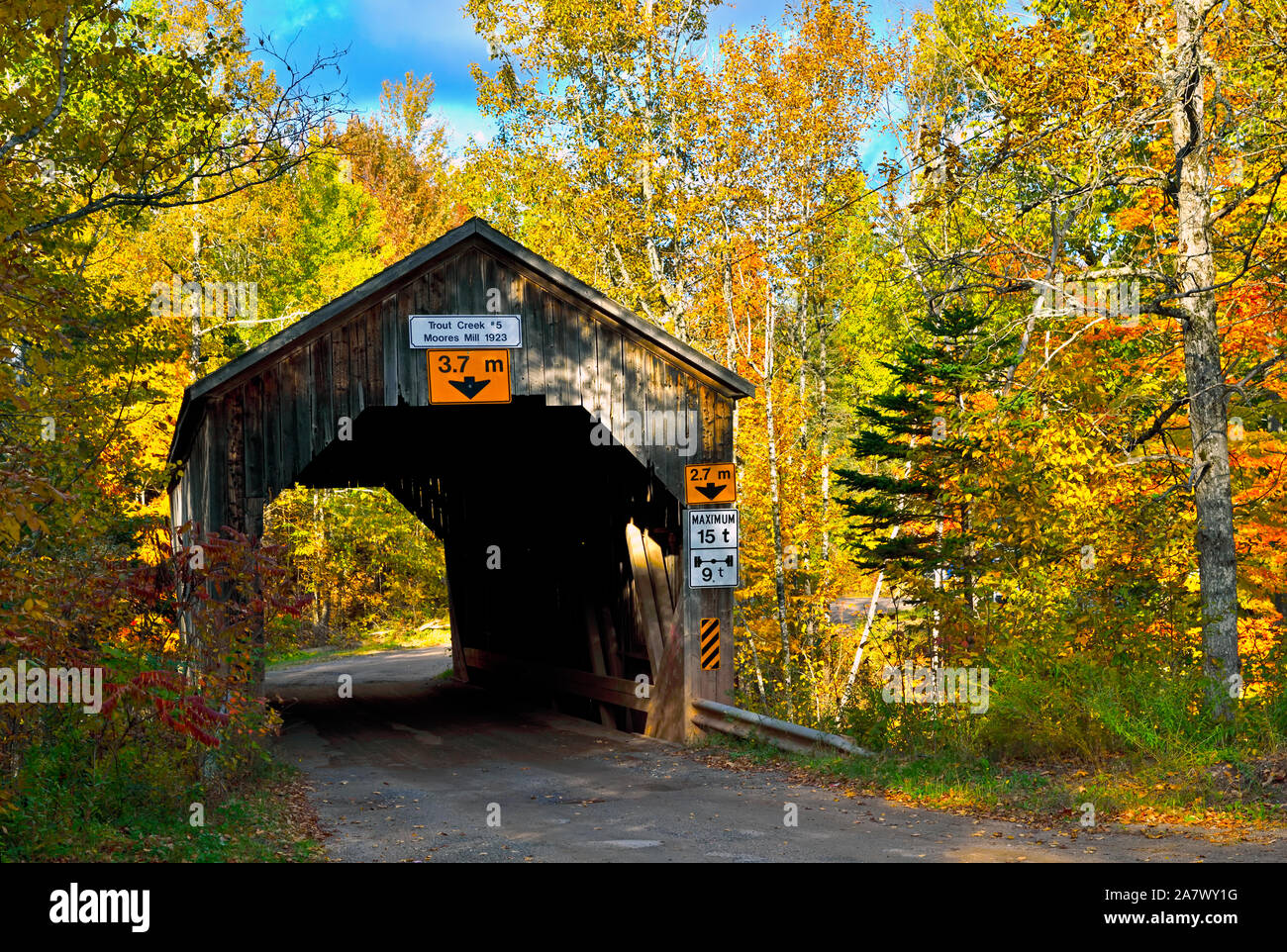 Un autunno immagine orizzontale di un iconico ponte coperto attraversando la trota torrente su un territorio rurale strada di ghiaia vicino a Sussex New Brunswick Canada. Foto Stock