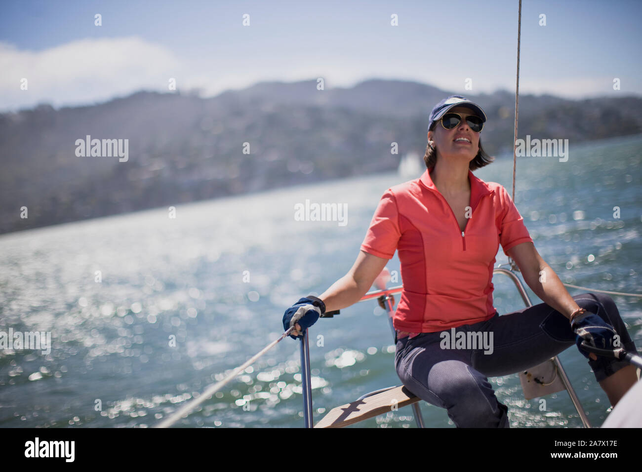 Mid-adulto donna seduta sulla prua di una barca a vela. Foto Stock