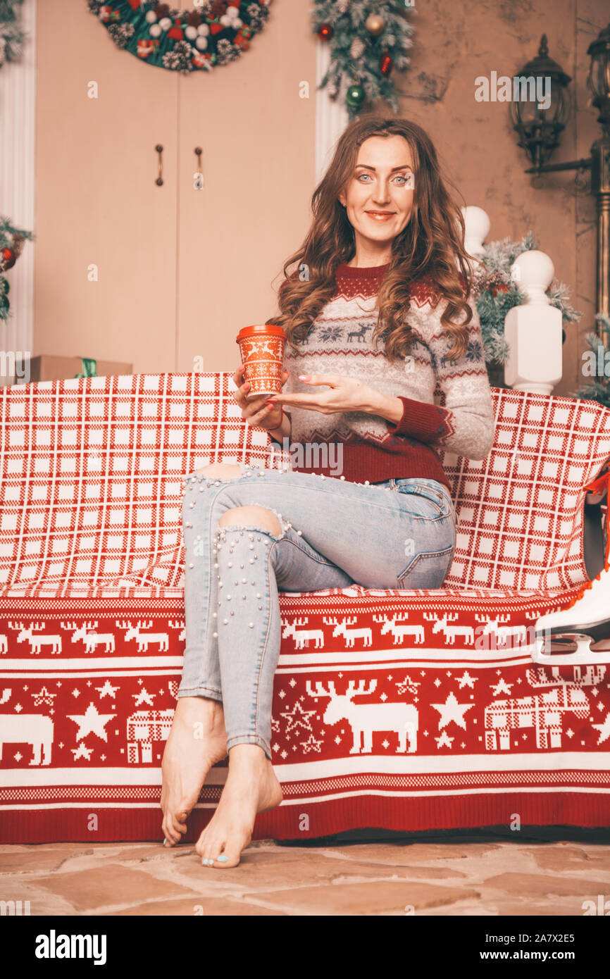 Affascinante ragazza sottile nel quartiere alla moda di jeans ricamato con  perle e maglione di Natale a piedi nudi seduta su una panchina a piena  lunghezza corpo Foto stock - Alamy