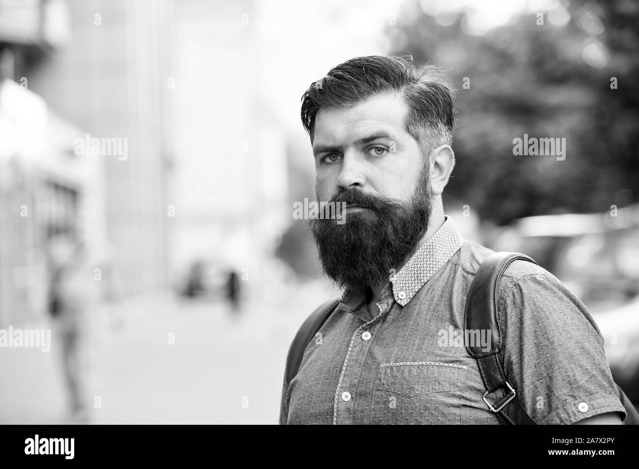 Guy esplorare la città. Turismo confortevole. La vacanza estiva. Hipster indossando uno zaino strada urbana dello sfondo. Uomo Barbuto viaggiare con lo zaino. Concetto di sightseeing. Zaino per il viaggio urbano. Foto Stock