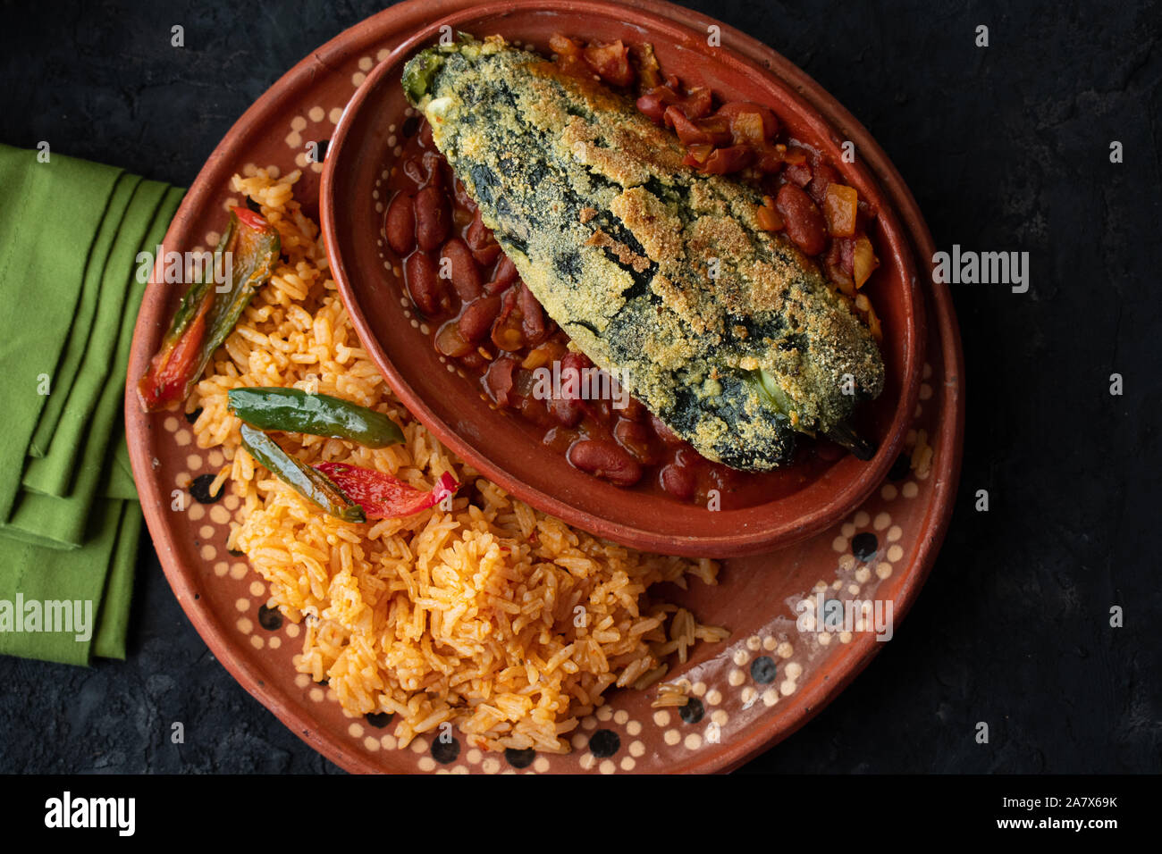 Chilles rellenos e riso messicano servita in tradizionali piastre di argilla Foto Stock
