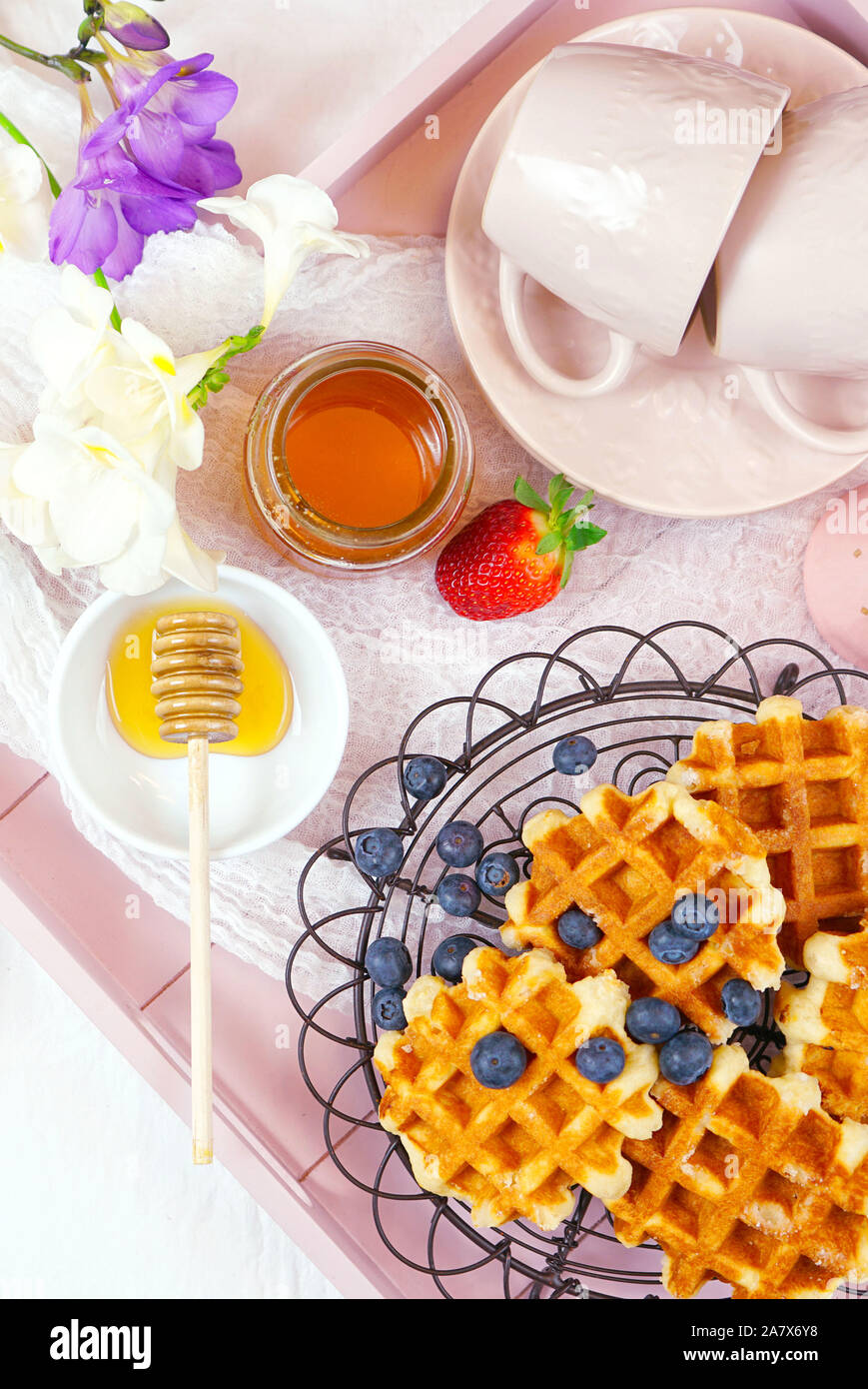 Moderno blush rosa vassoio colazione con cialde, miele e frutta piatto verticale lay close up. Foto Stock