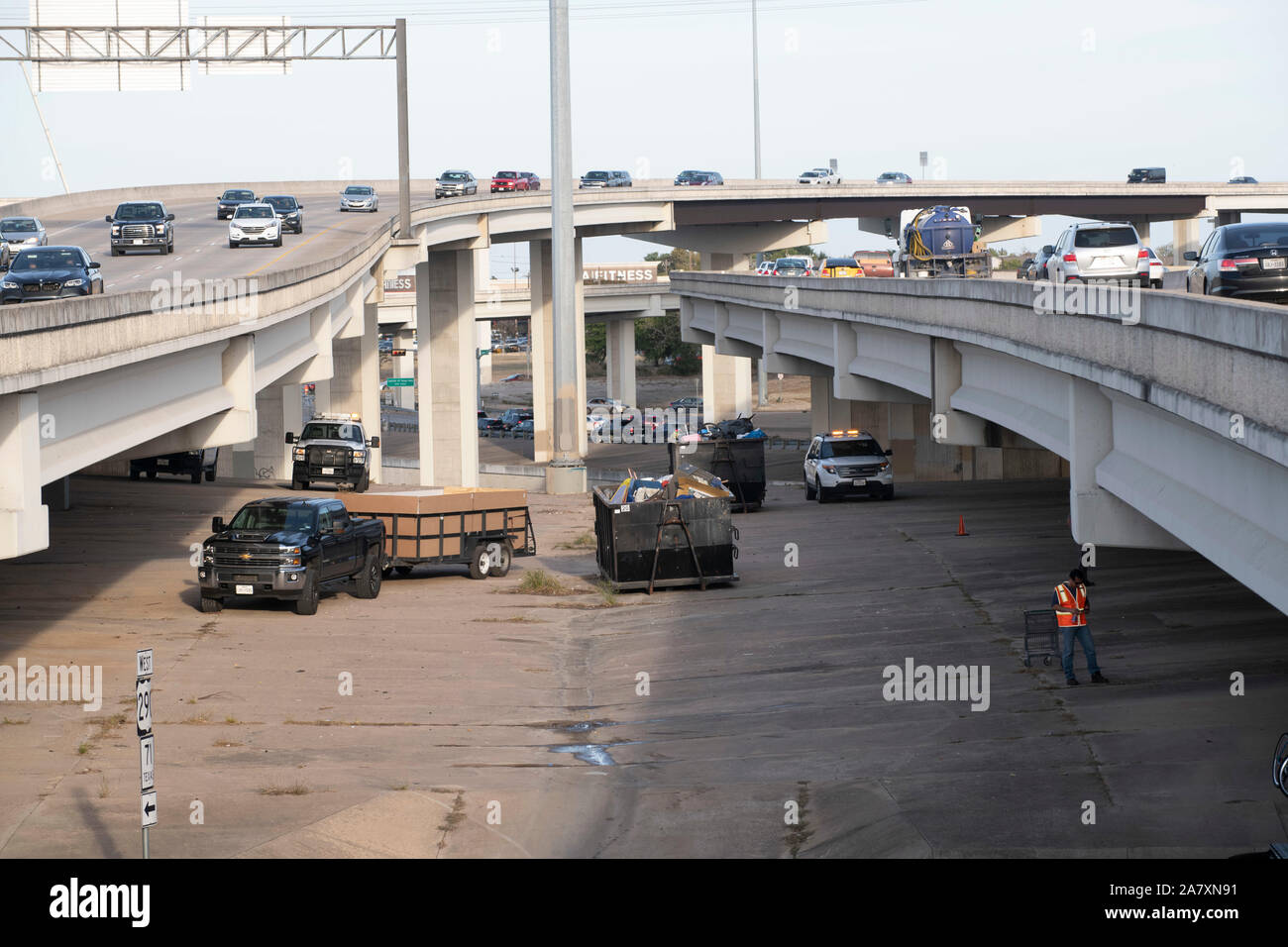 I lavoratori dal Texas Dipartimento Autostradale terminare la pulizia di un senzatetto encampment sul diritto pubblico-di-modo sotto un cavalcavia autostradale di Austin come ordinato dalla Texas Gov. Greg Abbott. Foto Stock