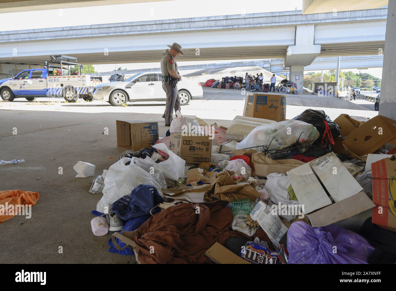 Austin, Texas, Stati Uniti d'America. 4 Novembre, 2019. Un Texas State trooper guarda oltre il cestino come autostrada dept. lavoratori terminare la pulizia il diritto di modo a U.S. La Highway 290 West di un senzatetto camp come ordinato dalla Texas Gov. Greg Abbott. Ci sono 17 siti identificati che verrà pulito nella prossima settimana. Credito: Bob Daemmrich/ZUMA filo/Alamy Live News Foto Stock