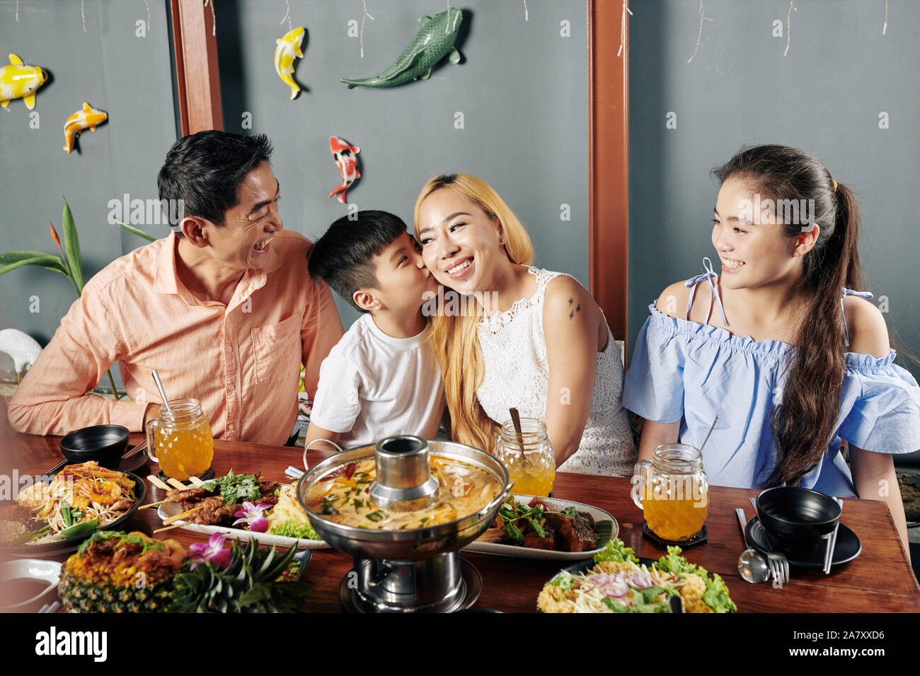 Little Boy baciare sua madre sulla guancia durante la cena di famiglia in cucina Asiatica ristorante Foto Stock