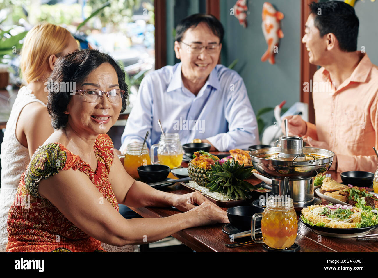 Felice senior donna asiatica in bicchieri di frequentare la famiglia cena in ristorante Foto Stock