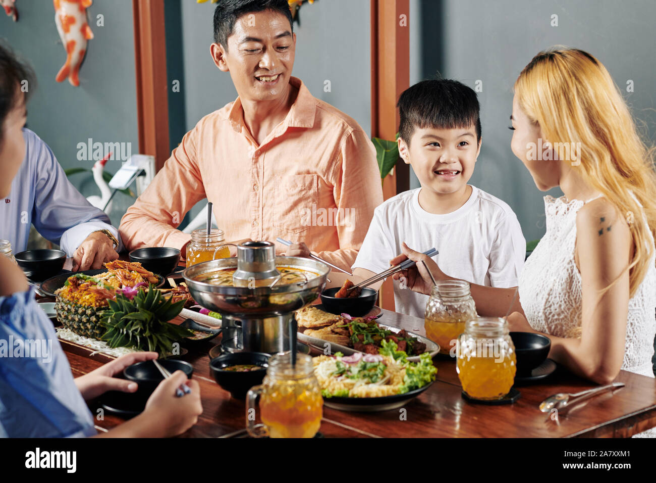 Allegra famiglia vietnamita gustando piatti della tradizionale cucina asiatica a cena nel ristorante Foto Stock