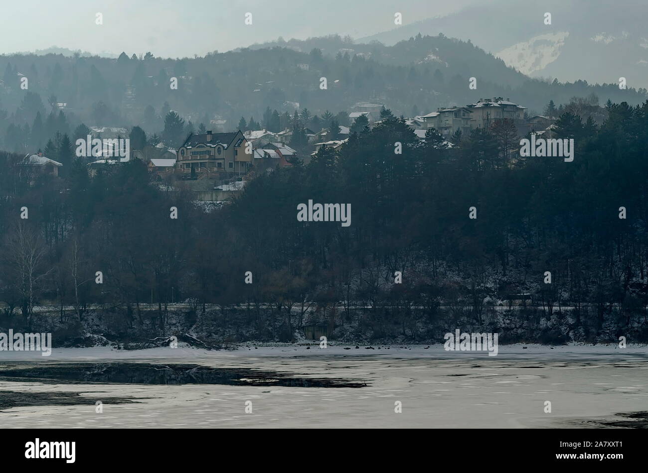 Scena invernale con lago ghiacciato, montagna innevata, glade, foresta e residenziale quartiere di borgo bulgaro Pancharevo, Sofia, Bulgaria Foto Stock