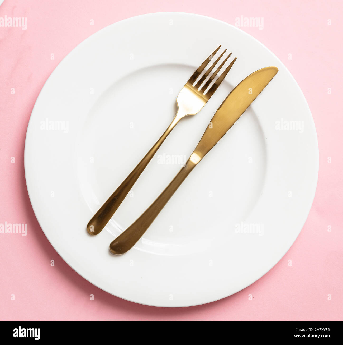 Oro e rosa lussuoso impostazione tabella. Golden set di posate e piatti bianchi contro sfondo rosa. Vista superiore, spazio di copia Foto Stock