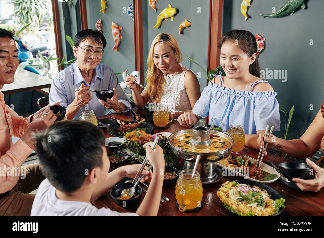 Grande e felice famiglia vietnamita di mangiare piatti saporiti della cucina asiatica al grande tavolo nel ristorante Foto Stock