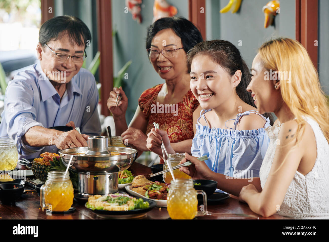 Felice ragazza preteen mangiare una gustosa cena con la sua famiglia nel ristorante quando celebrare qualche evento insieme Foto Stock