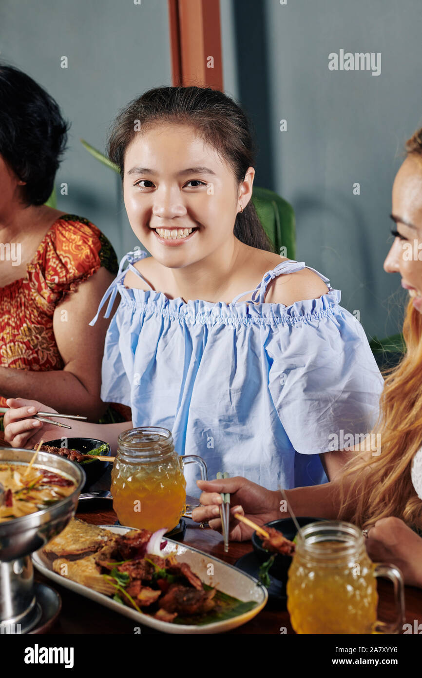 Ritratto di bella sorridente ragazza vietnamita di mangiare la cena con bacchette e guardando la fotocamera Foto Stock