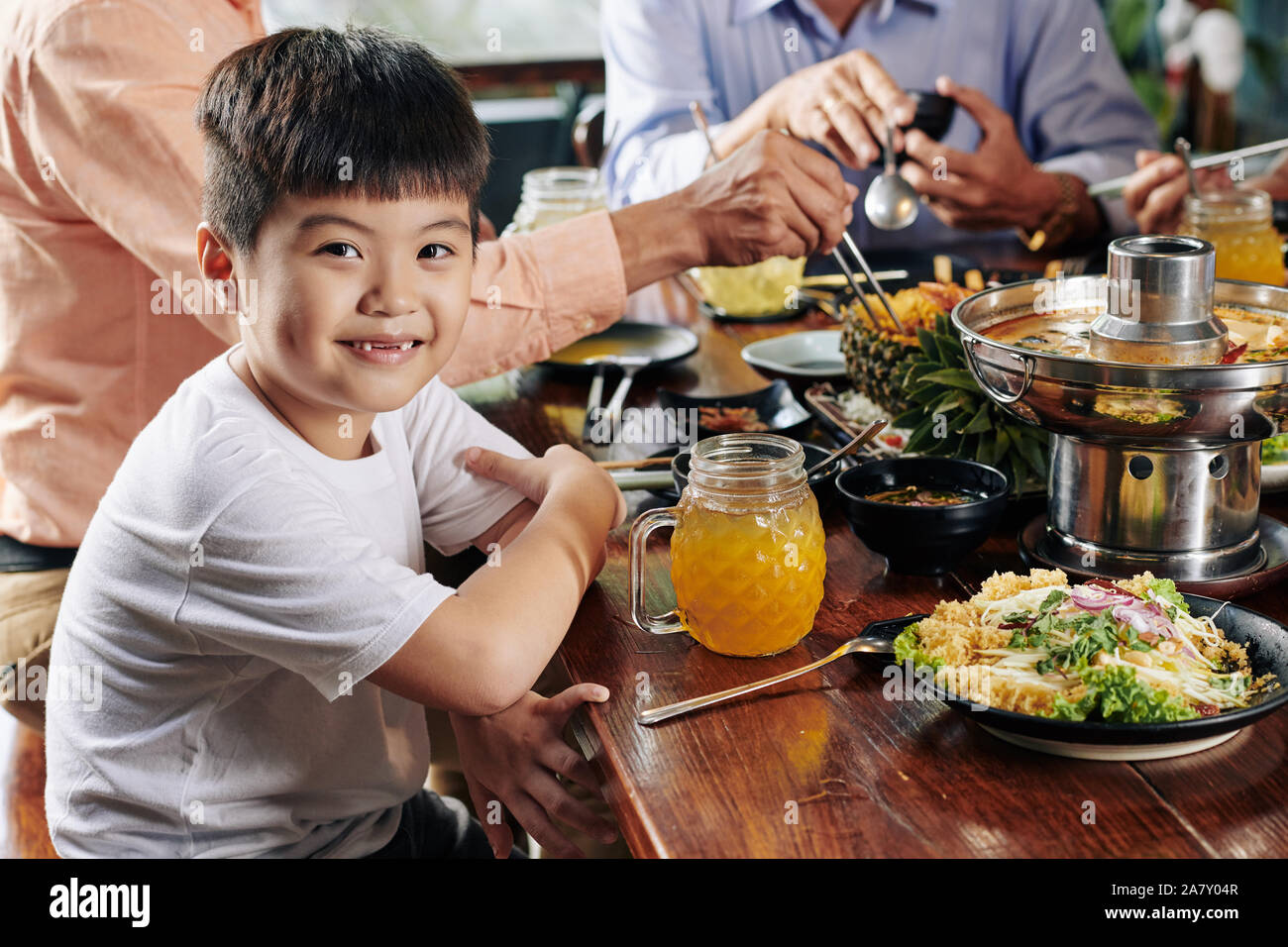 Ritratto di poco sorridente ragazzo asiatico mangiare piatti saporiti della cucina vietnamita a cena in famiglia Foto Stock