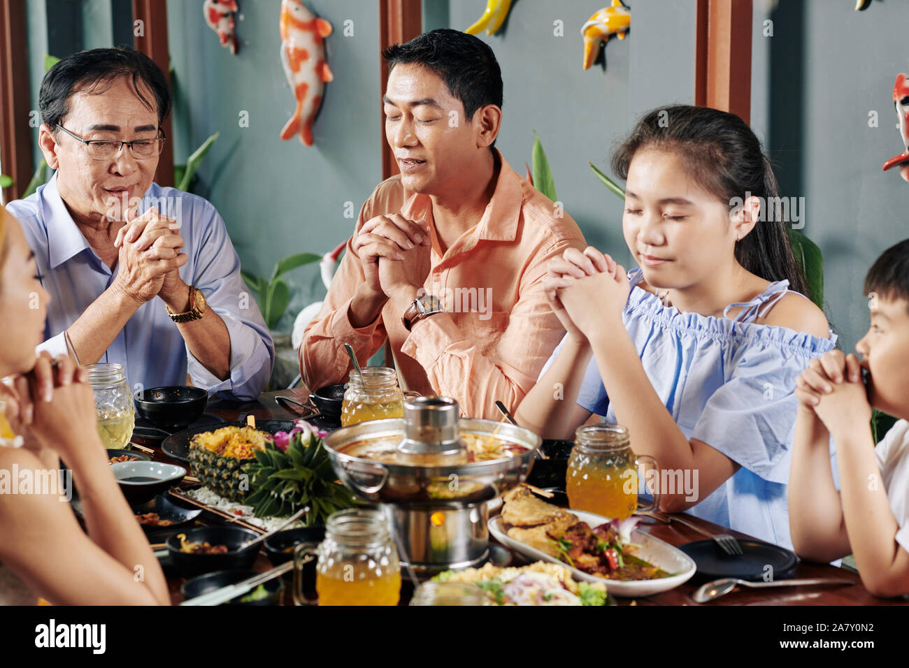 Il vietnamita familiari chiudendo gli occhi quando pregare prima di cena a casa Foto Stock