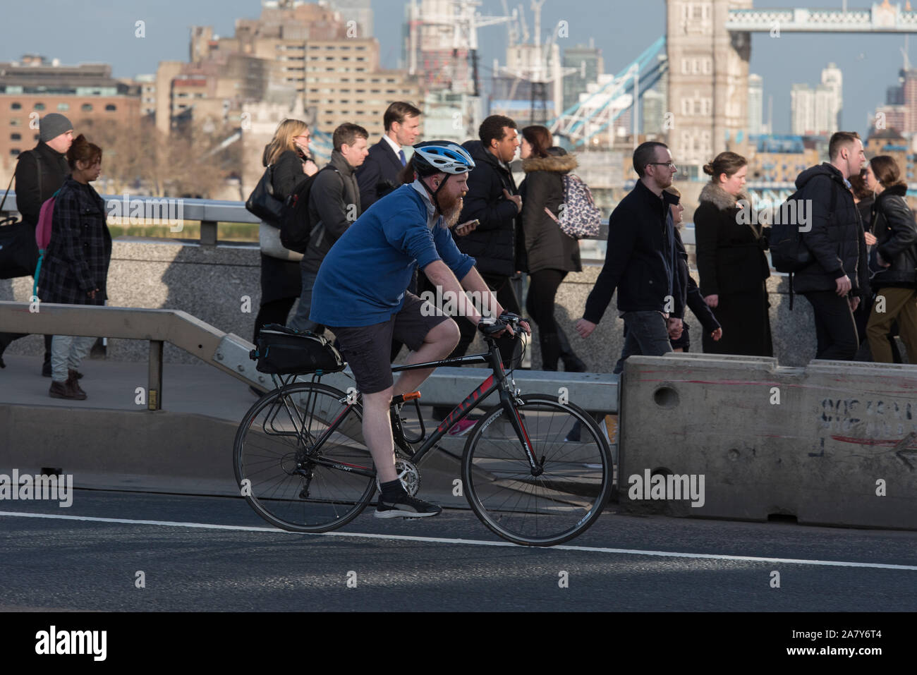 Pendolari sul piede e un ciclista sul ponte di Londra in serata durante le ore di punta, Londra, Regno Unito. Foto Stock