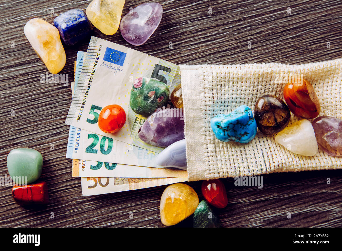 Sacco di diverso colore e tipo semi pietre preziose con denaro euro banconote. Hobby costoso pietra concetto di collettore. Foto Stock