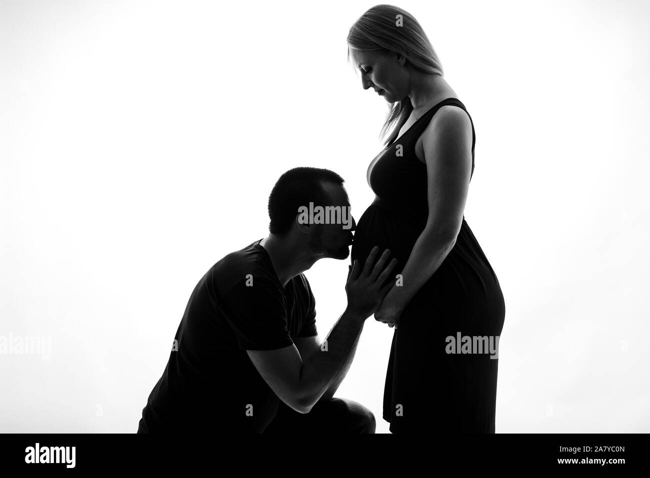 Silhouette ritratto del marito baciare uomo donna incinta pancia. Giovane coppia in gravidanza in amore aspetta bambino, studioportrait. Silhouette isolata w Foto Stock