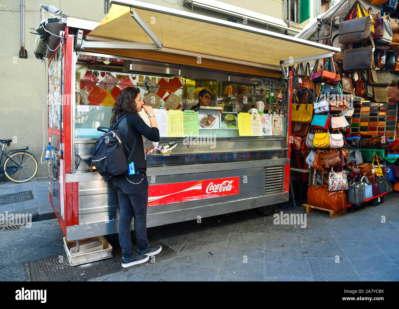 Donna di mangiare un panino con il lampredotto, una tipica trippa alla fiorentina della cucina di strada, di fronte un chiosco nel centro di Firenze, Toscana, Italia Foto Stock