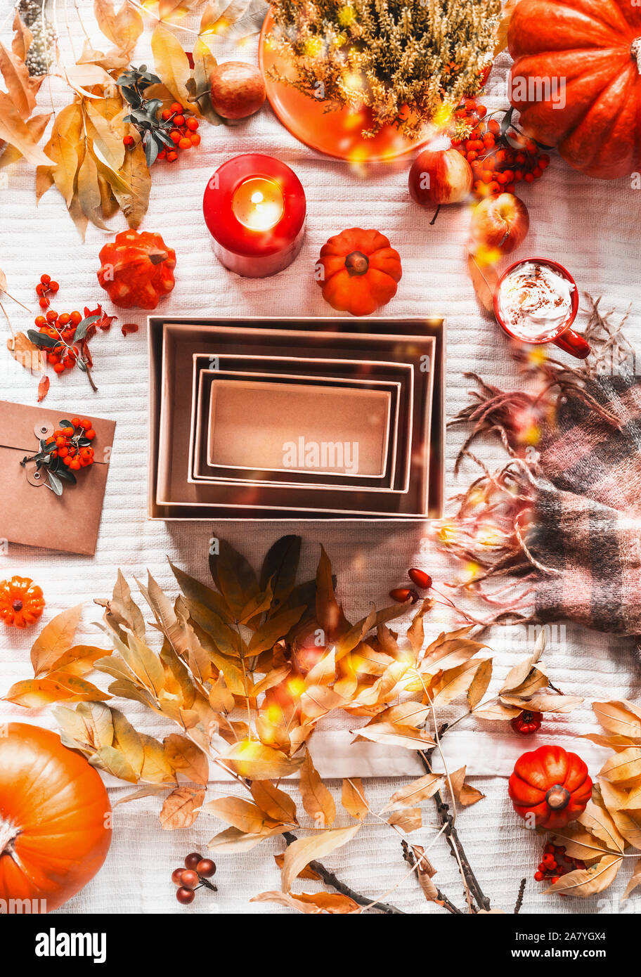 Piatto autunnale lay con vuoto di carta kraft scatole, sciarpa, foglie di autunno, zucche, candele e cappuccino, vista dall'alto. Moda o scatola di bellezza. Posto che fa per voi Foto Stock
