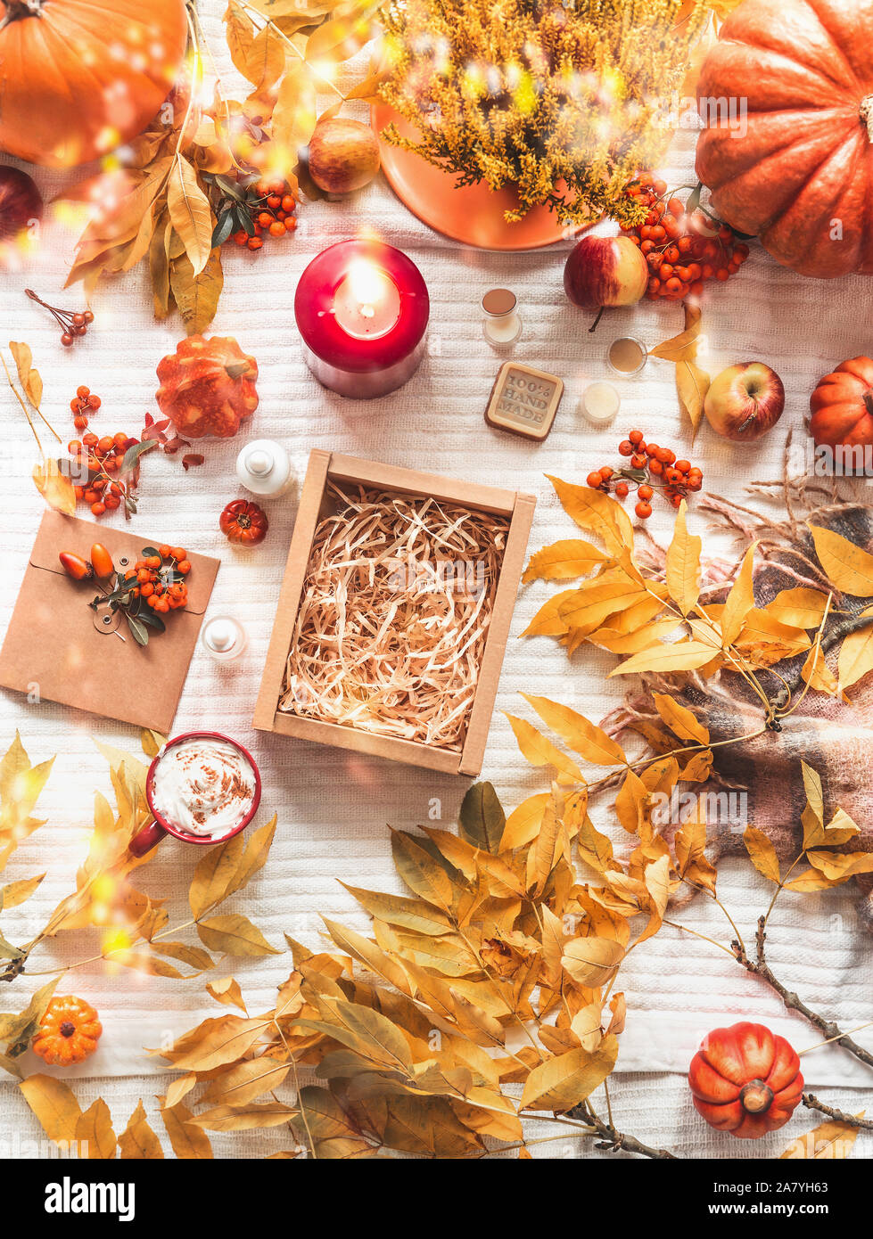 Svuotare la carta kraft box su coltre bianca con rami di autunno e cadono le foglie, cappuccino, prodotti cosmetici, candela che brucia, zucca e rowan. Zero wa Foto Stock
