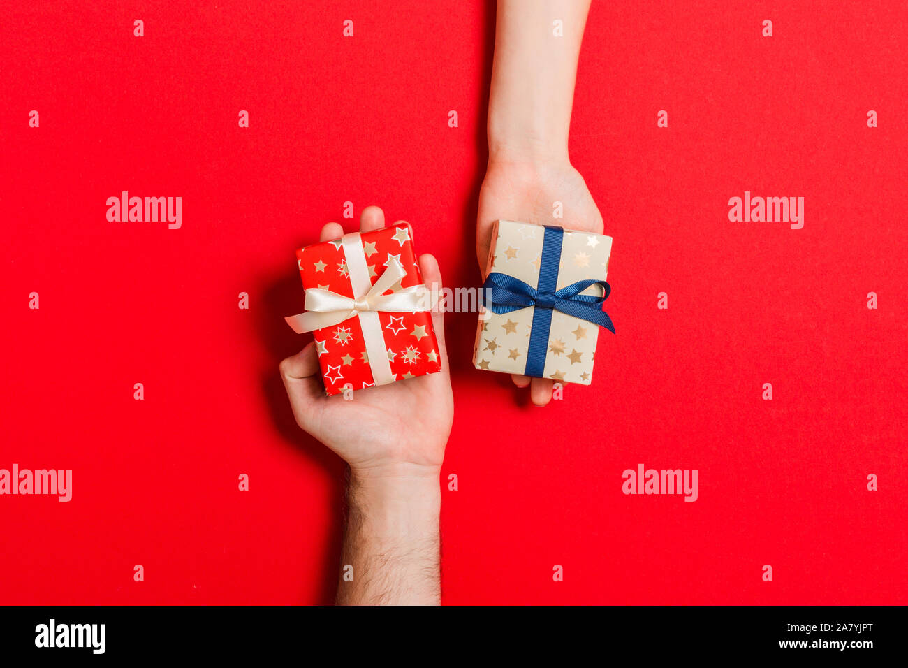 Vista dall'alto di una donna e un uomo lo scambio di doni su sfondo colorato. Paio di regalare a ogni altro. Rendendo la sorpresa per il concetto di vacanza con co Foto Stock