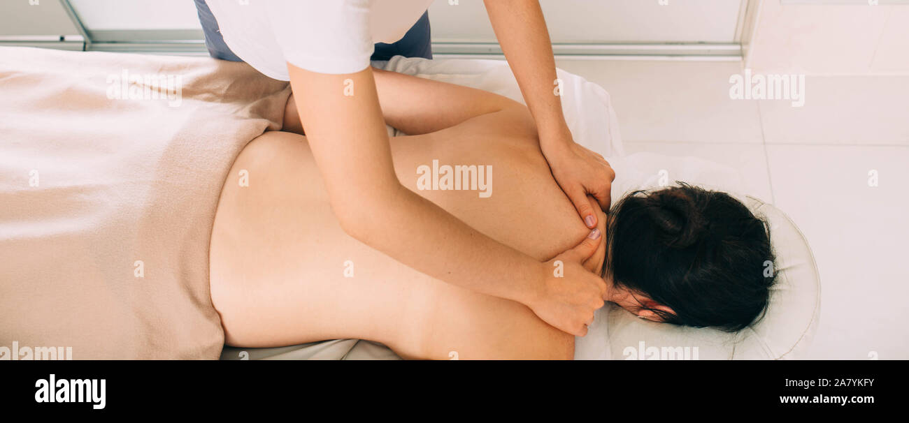 Vista superiore della donna sdraiata su un lettino da massaggio e ricevere il massaggio della schiena, spa weekend Foto Stock